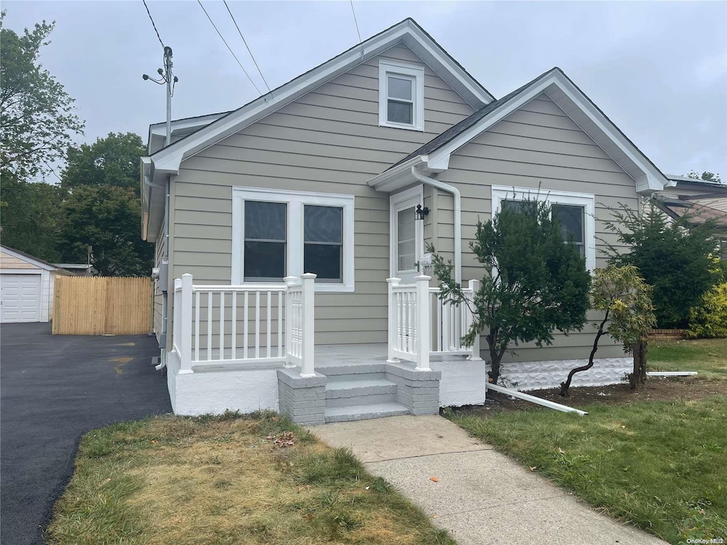 bungalow with a garage, an outbuilding, and a front lawn