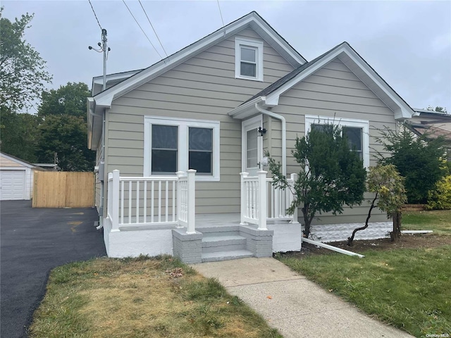 bungalow with a garage, an outbuilding, and a front lawn