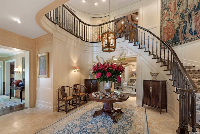 staircase featuring a towering ceiling and crown molding