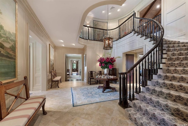 entryway featuring a towering ceiling and ornamental molding