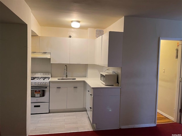 kitchen featuring backsplash, sink, white cabinets, and range with gas cooktop