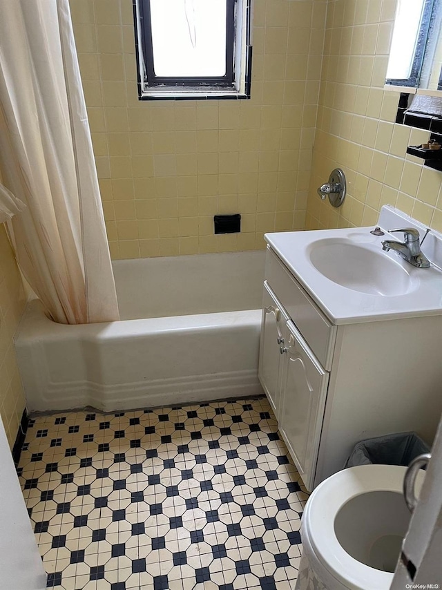 bathroom with shower / bath combination with curtain, tile walls, and sink