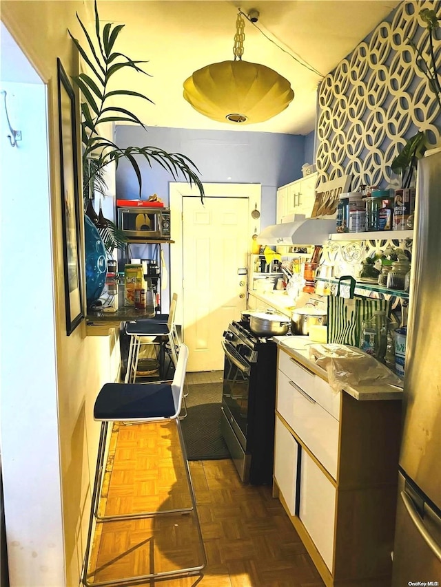 kitchen featuring dark parquet flooring, white cabinets, stainless steel appliances, and ventilation hood