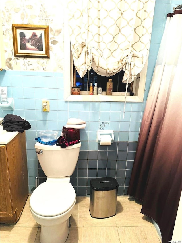 bathroom featuring tile patterned flooring, toilet, and tile walls