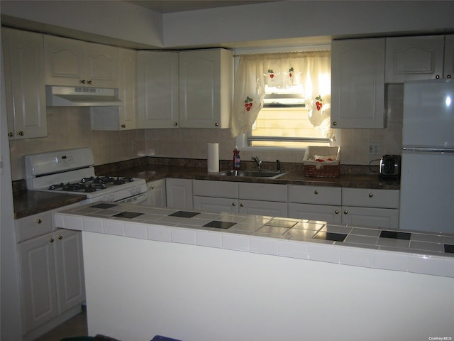 kitchen with tile countertops, white cabinets, white appliances, and sink