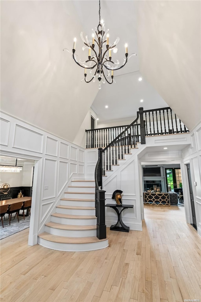 stairway featuring a fireplace, a high ceiling, a decorative wall, and wood finished floors