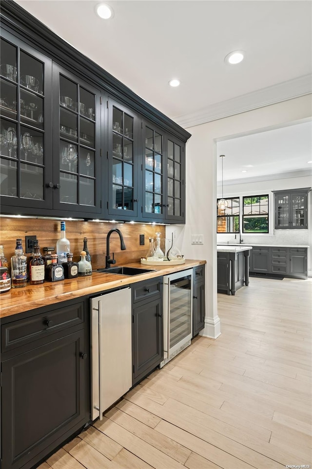 bar with wine cooler, refrigerator, wet bar, crown molding, and a sink