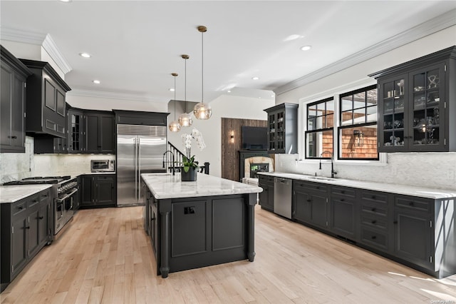 kitchen with a center island, ornamental molding, a sink, high quality appliances, and dark cabinetry