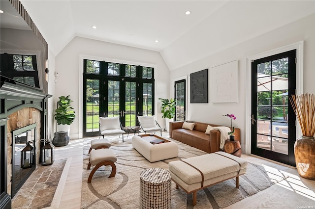 living area with lofted ceiling, recessed lighting, a fireplace, and french doors