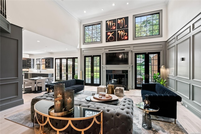 living room with ornamental molding, french doors, a decorative wall, and a towering ceiling