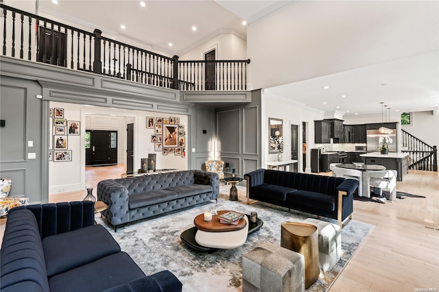 living room with crown molding, recessed lighting, light wood-style flooring, stairway, and a high ceiling