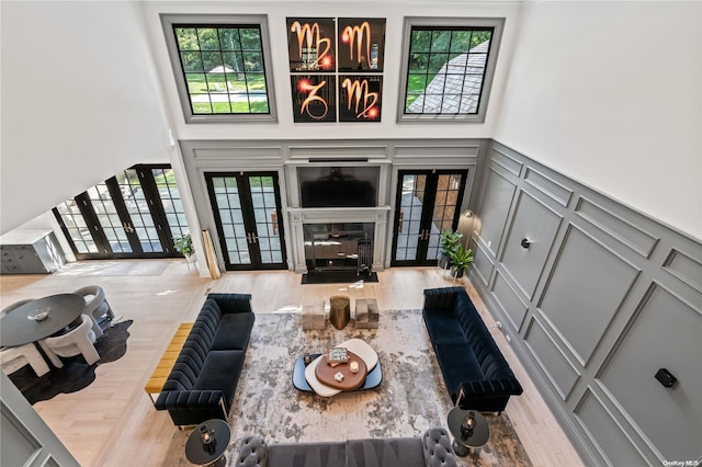 living area with a healthy amount of sunlight, a decorative wall, and french doors