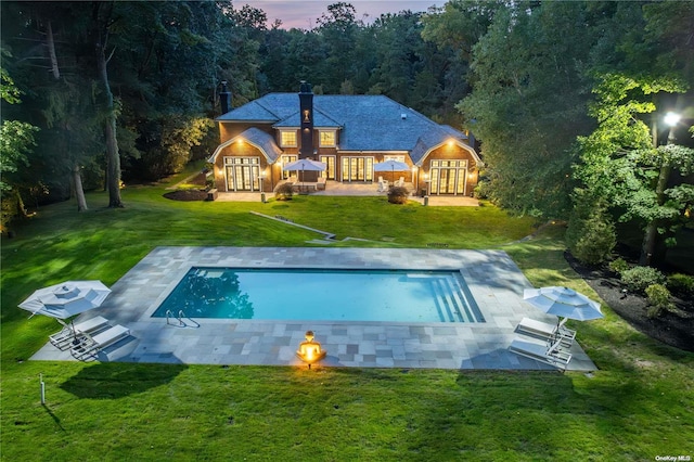 back of property featuring a yard, an outdoor pool, a patio, and french doors