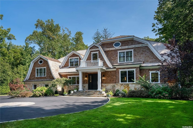 view of front of home with a balcony and a front lawn