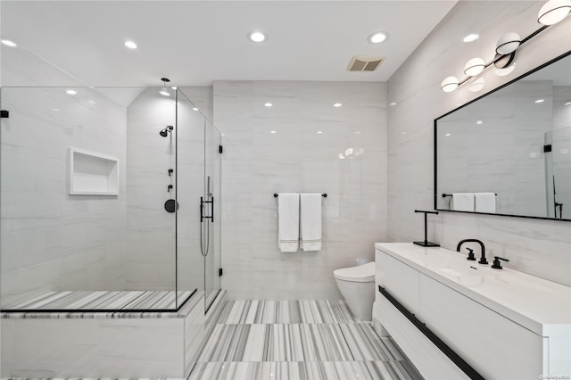 bathroom with toilet, vanity, visible vents, tile walls, and a stall shower