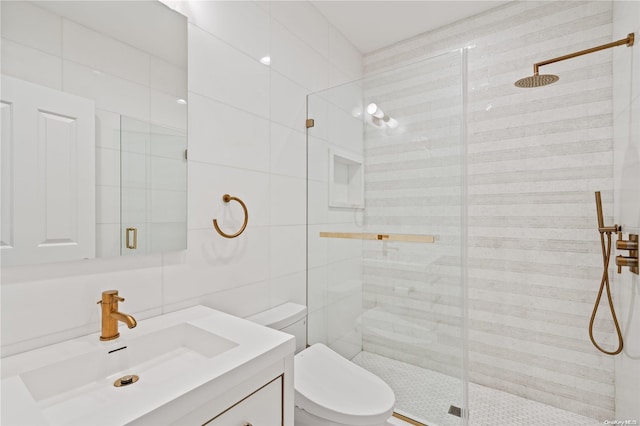 bathroom featuring toilet, a stall shower, vanity, and tile walls