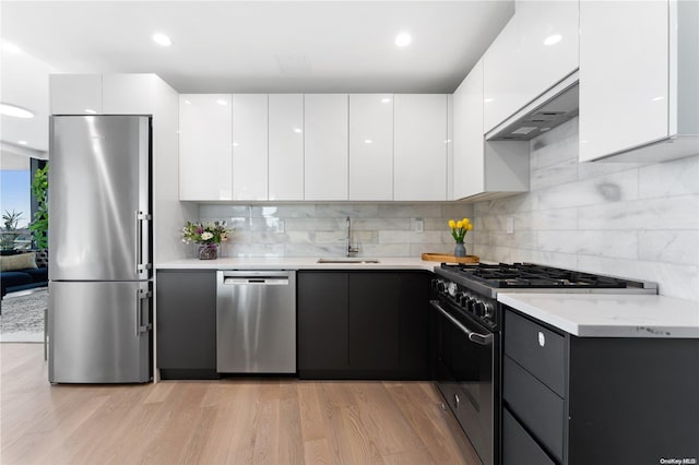 kitchen with white cabinetry, sink, stainless steel appliances, and light hardwood / wood-style flooring