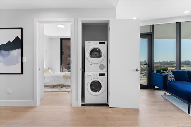 laundry area with stacked washer and dryer and light hardwood / wood-style flooring