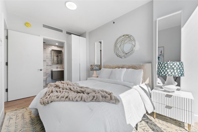 bedroom featuring hardwood / wood-style floors and ensuite bathroom