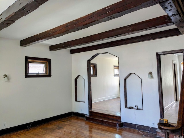 empty room featuring beamed ceiling and dark hardwood / wood-style floors