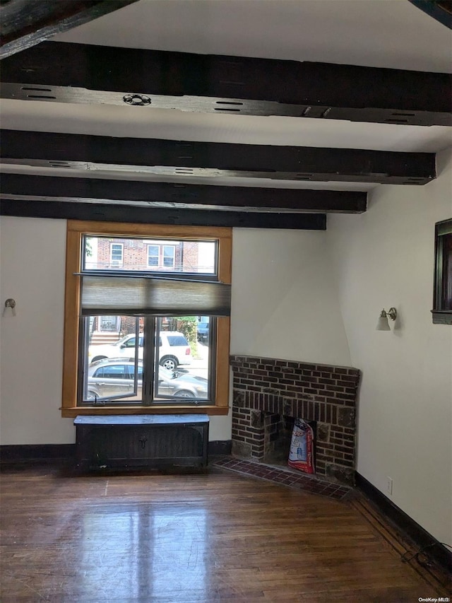 unfurnished living room with hardwood / wood-style flooring, beam ceiling, and a brick fireplace