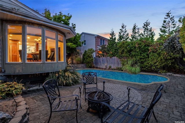 pool at dusk featuring a patio and an outdoor fire pit