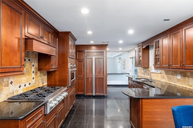 kitchen with dark stone counters, sink, tasteful backsplash, kitchen peninsula, and stainless steel appliances