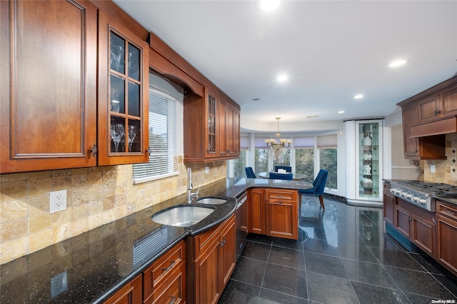 kitchen with a notable chandelier, backsplash, sink, appliances with stainless steel finishes, and decorative light fixtures