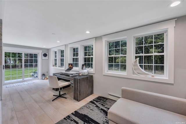 home office featuring a healthy amount of sunlight, light wood-type flooring, and a baseboard heating unit