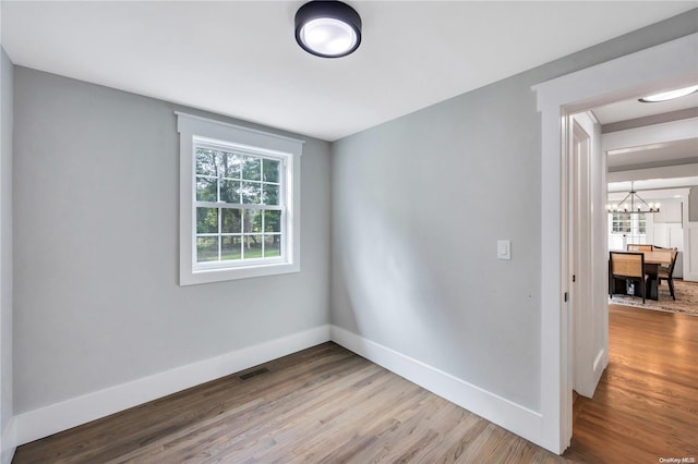 unfurnished room featuring light hardwood / wood-style floors and a notable chandelier