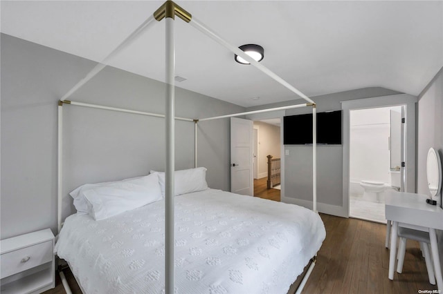 bedroom with lofted ceiling, connected bathroom, and dark wood-type flooring