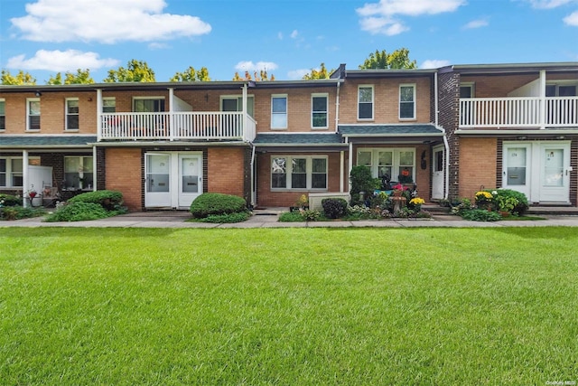 view of front of house featuring a balcony and a front lawn