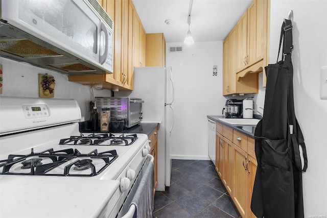 kitchen featuring track lighting, white appliances, dark tile patterned floors, sink, and light brown cabinets