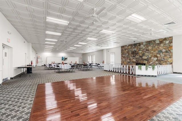 misc room featuring hardwood / wood-style floors, ceiling fan, and a towering ceiling