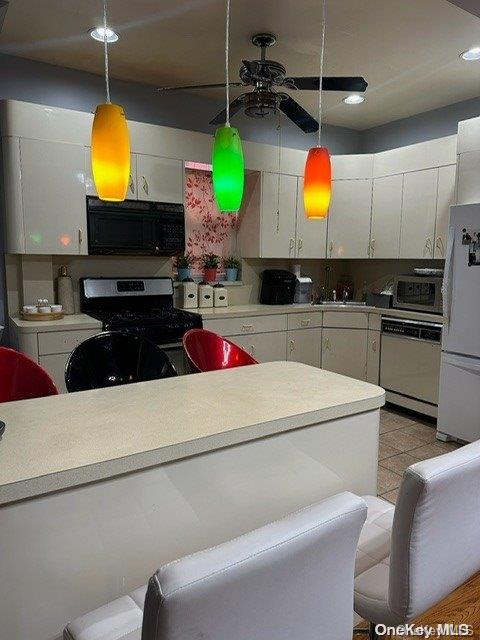 kitchen with white cabinetry, ceiling fan, black appliances, and decorative light fixtures