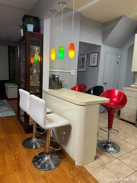 bar with pendant lighting, white cabinetry, and light hardwood / wood-style flooring