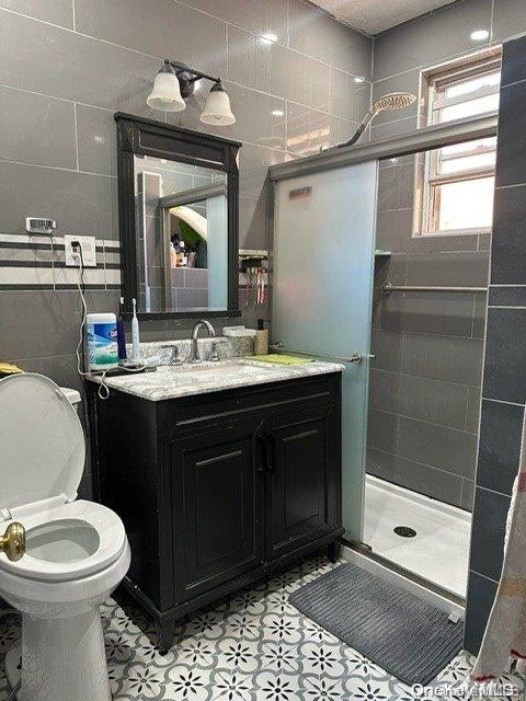 bathroom with vanity, toilet, walk in shower, and tile walls