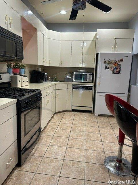 kitchen with white cabinetry, light tile patterned floors, and black appliances