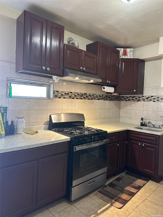 kitchen with light tile patterned flooring, decorative backsplash, sink, and stainless steel range with gas stovetop