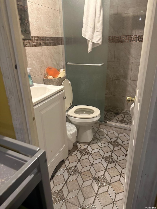 bathroom featuring tile patterned flooring, vanity, toilet, and walk in shower