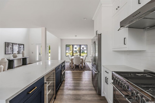 kitchen featuring white cabinets, premium appliances, dark hardwood / wood-style floors, and beverage cooler