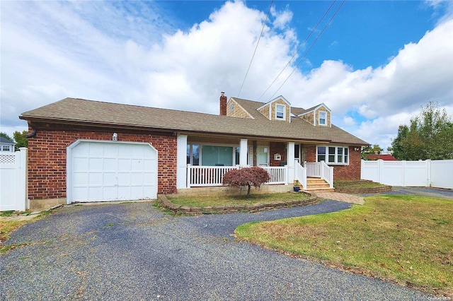 cape cod house with covered porch, a garage, and a front lawn