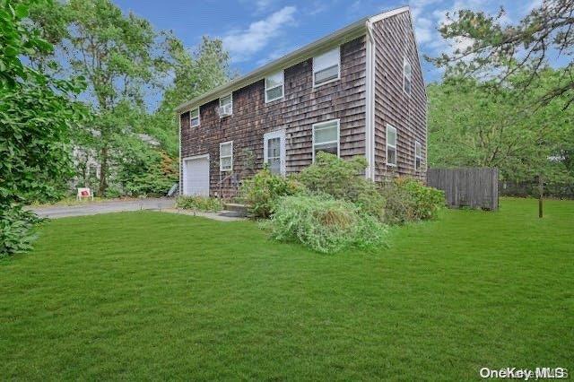 rear view of property featuring a garage and a yard