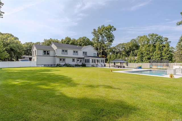 rear view of property featuring a gazebo, a lawn, and a fenced in pool