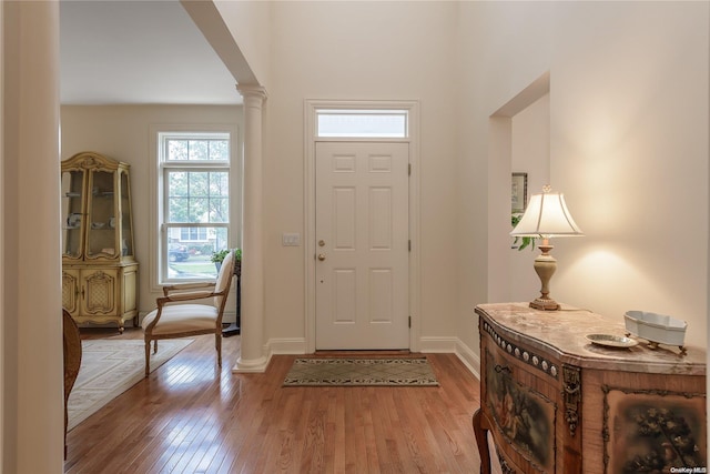 foyer featuring decorative columns and light wood-type flooring