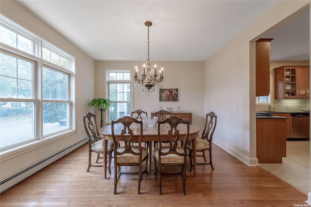 dining area with light hardwood / wood-style floors, an inviting chandelier, and a baseboard heating unit