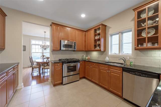 kitchen featuring pendant lighting, sink, appliances with stainless steel finishes, tasteful backsplash, and a chandelier