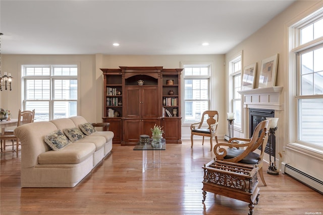 living room with a chandelier, light hardwood / wood-style floors, and a baseboard radiator