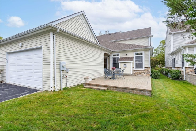 back of property with a patio, a garage, and a lawn