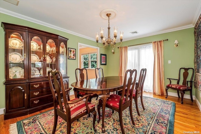 dining room featuring crown molding, light hardwood / wood-style flooring, and a chandelier